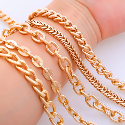 Close-up of a hand wearing multiple gold-tone chain bracelets, including curb, rope, and link styles, against a clean white background.