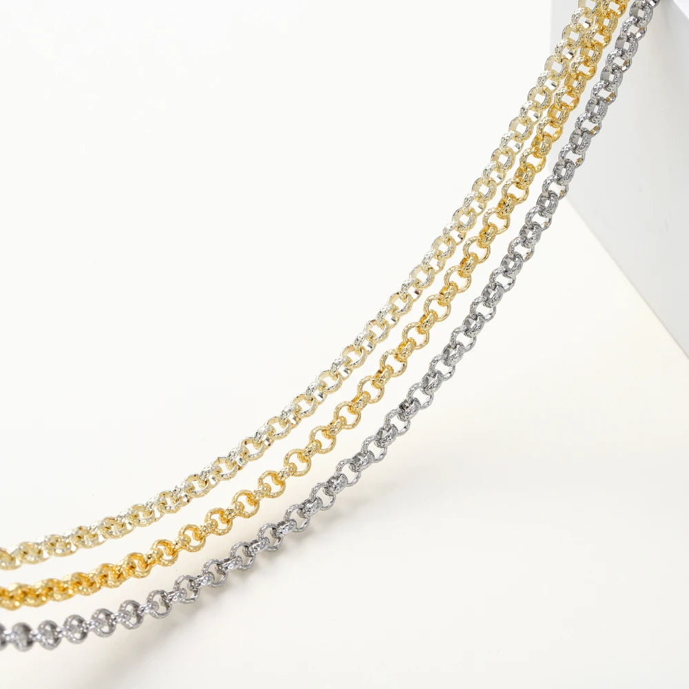 Three layered chain necklaces in yellow gold, silver, and white gold, arranged diagonally on a clean white background.