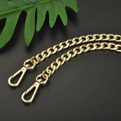 Gold chain with clasp on a dark background with green leaves