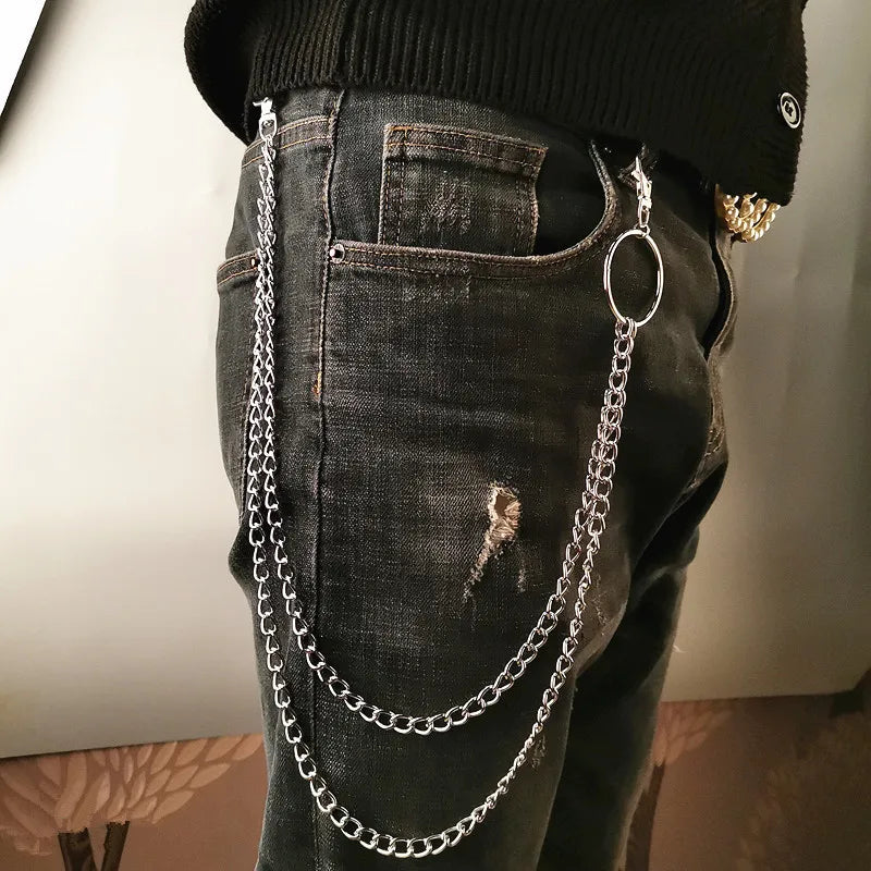 Person wearing dark jeans with silver chain details on a neutral background