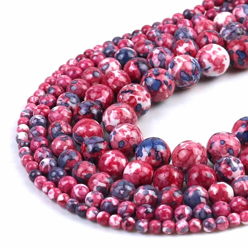 Multiple strands of round gemstone beads in a marbled pattern of red, pink, white, and dark blue, arranged in a curve on a white background.