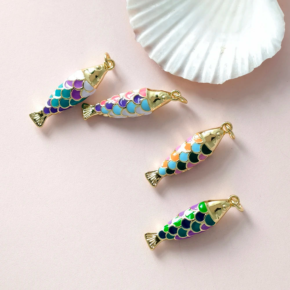 Colorful fish-shaped charms with gold accents on a light pink background