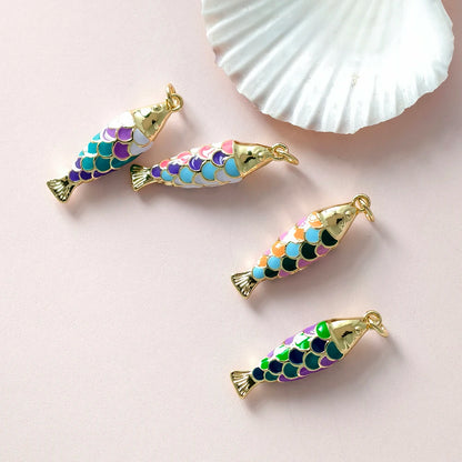 Colorful fish-shaped charms with gold accents on a light pink background