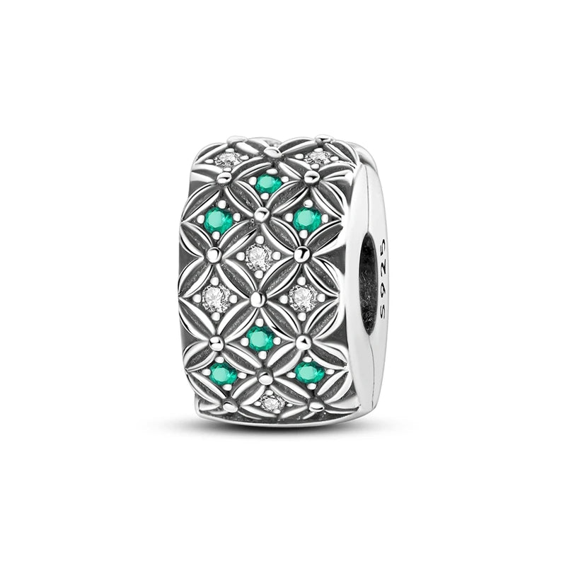 Silver charm with green gemstones and clear stones on a white background