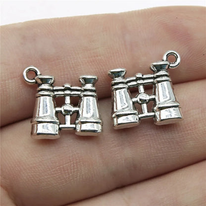 Silver binocular-shaped charms on a person's hand