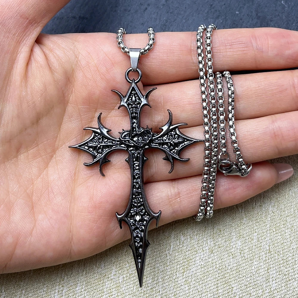 Hand holding a detailed silver cross pendant with chain