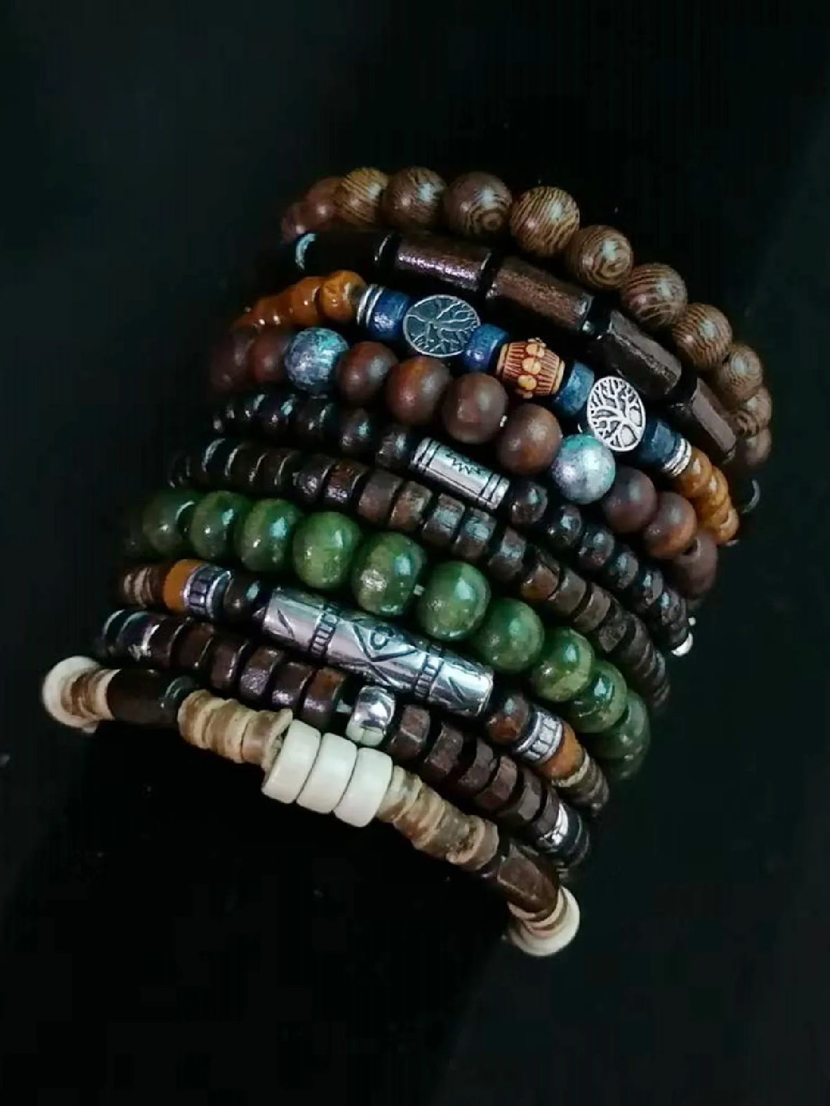 Stack of beaded bracelets with various colors and metal accents on a dark background