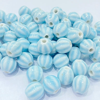 A pile of glossy, light blue and white striped round beads with a central hole, arranged on a plain white background.