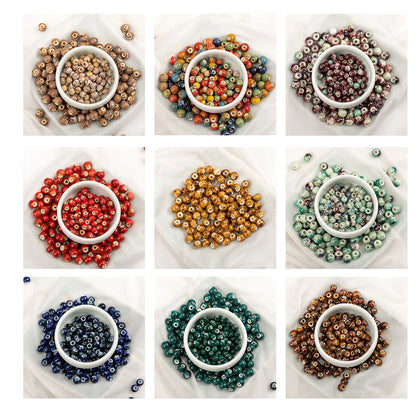 A 3x3 grid showing nine different colors of small round glass beads, each arranged in a small white bowl on a white fabric background.