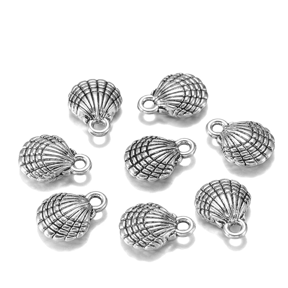 Nine silver-toned shell-shaped jewelry charms with textured ribbed details and small loops, arranged on a plain white background.