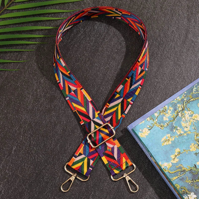 Colorful geometric-patterned strap on a dark surface with a floral notebook.