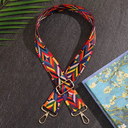 Colorful geometric-patterned strap on a dark surface with a floral notebook.
