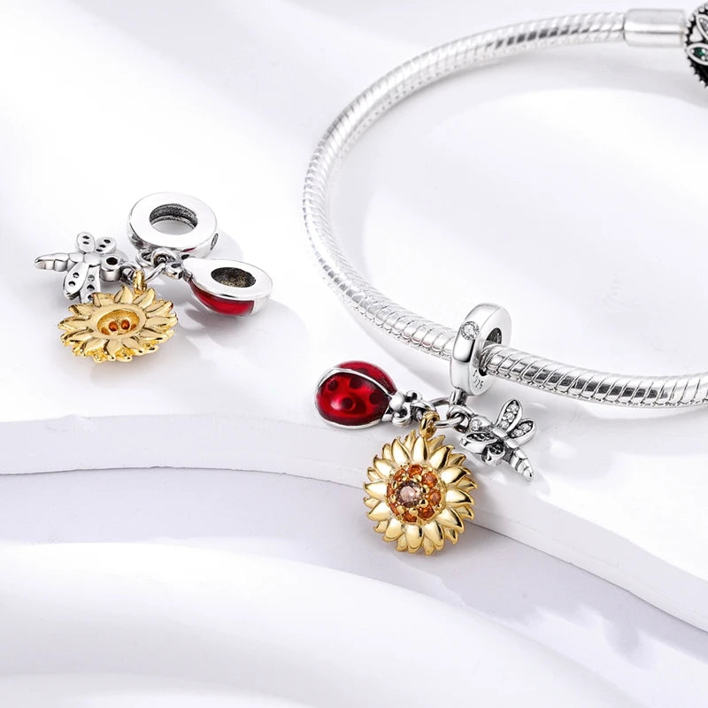 Silver bracelet with various charms including a sun, starfish, and ladybug on a white background