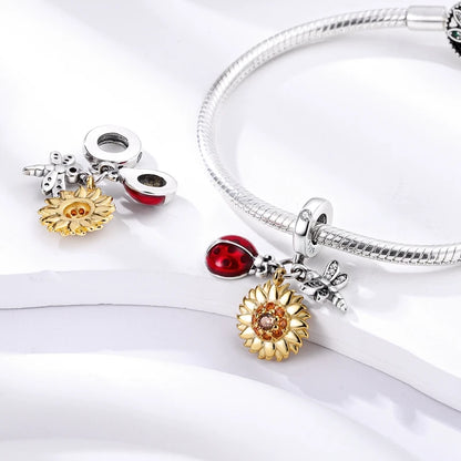 Silver bracelet with various charms including a sun, starfish, and ladybug on a white background
