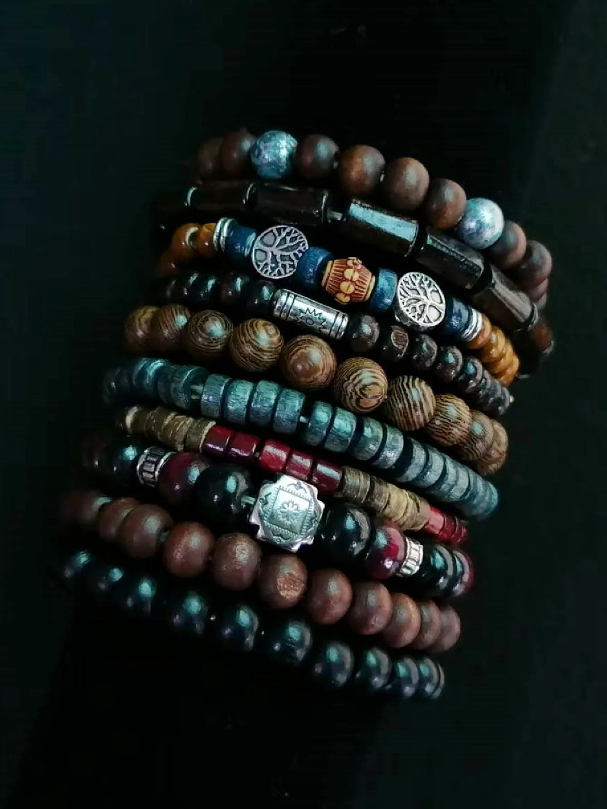 Stack of multicolored beaded bracelets with metal charms on a dark background
