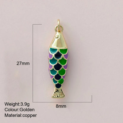 Gold fish-shaped pendant with green and purple scales on a light gray background