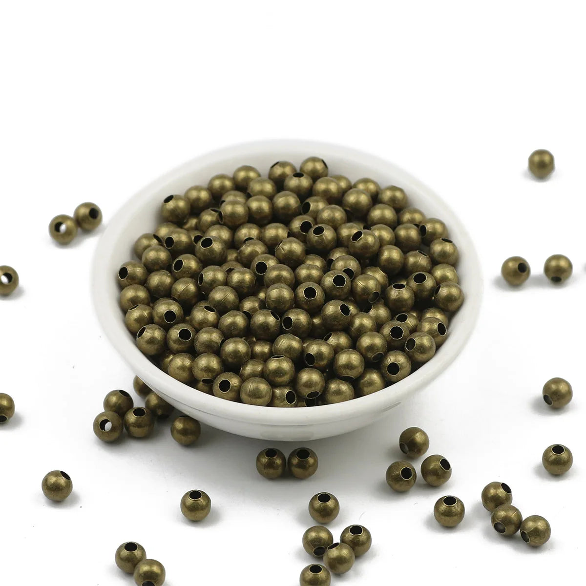 Bronze beads in a white bowl on a white background
