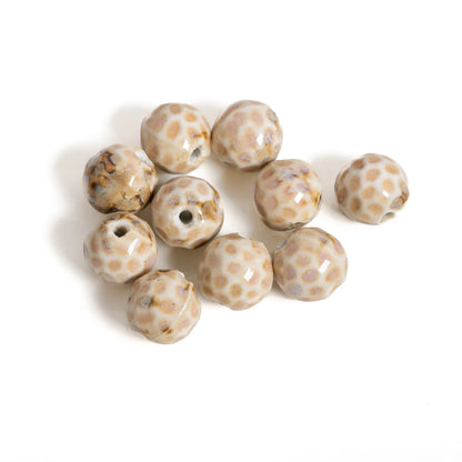 Nine round glass beads with a beige and brown spotted pattern, arranged on a plain white background.