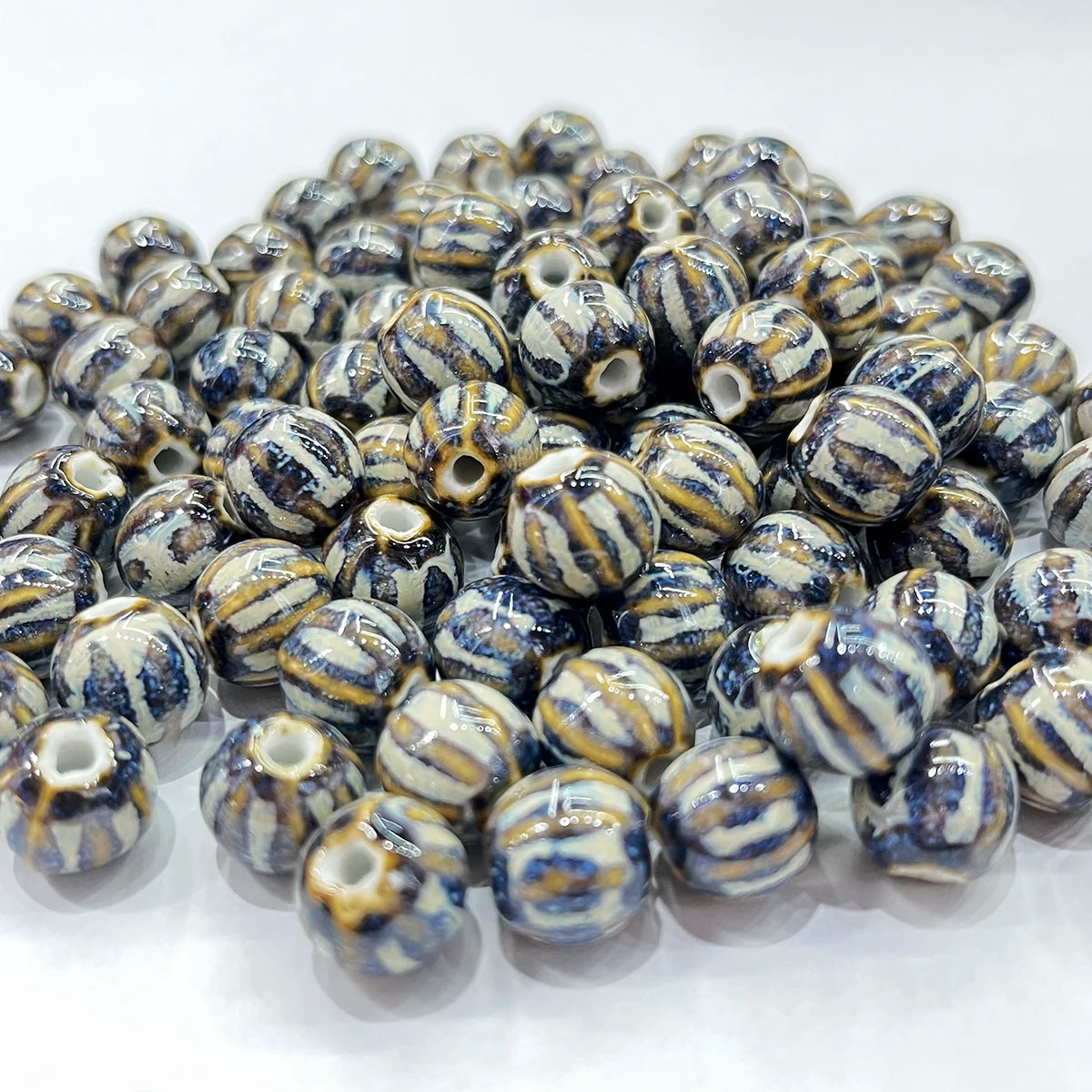 A pile of round ceramic beads with a glossy finish, featuring a marbled pattern of navy blue, cream, and light brown.