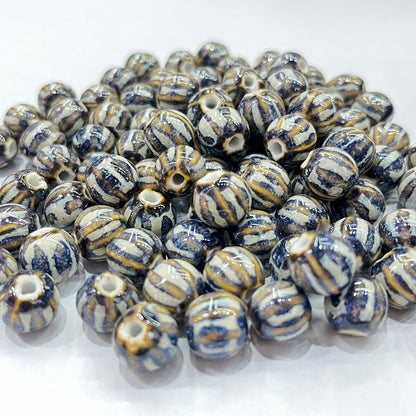 A pile of round ceramic beads with a glossy finish, featuring a marbled pattern of navy blue, cream, and light brown.