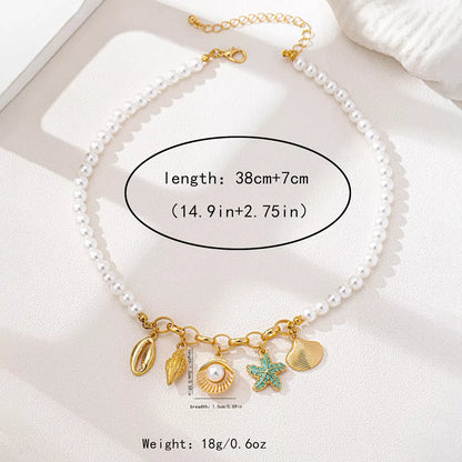 Pearl necklace with gold and green sea charms on a white surface, showing length and weight information.